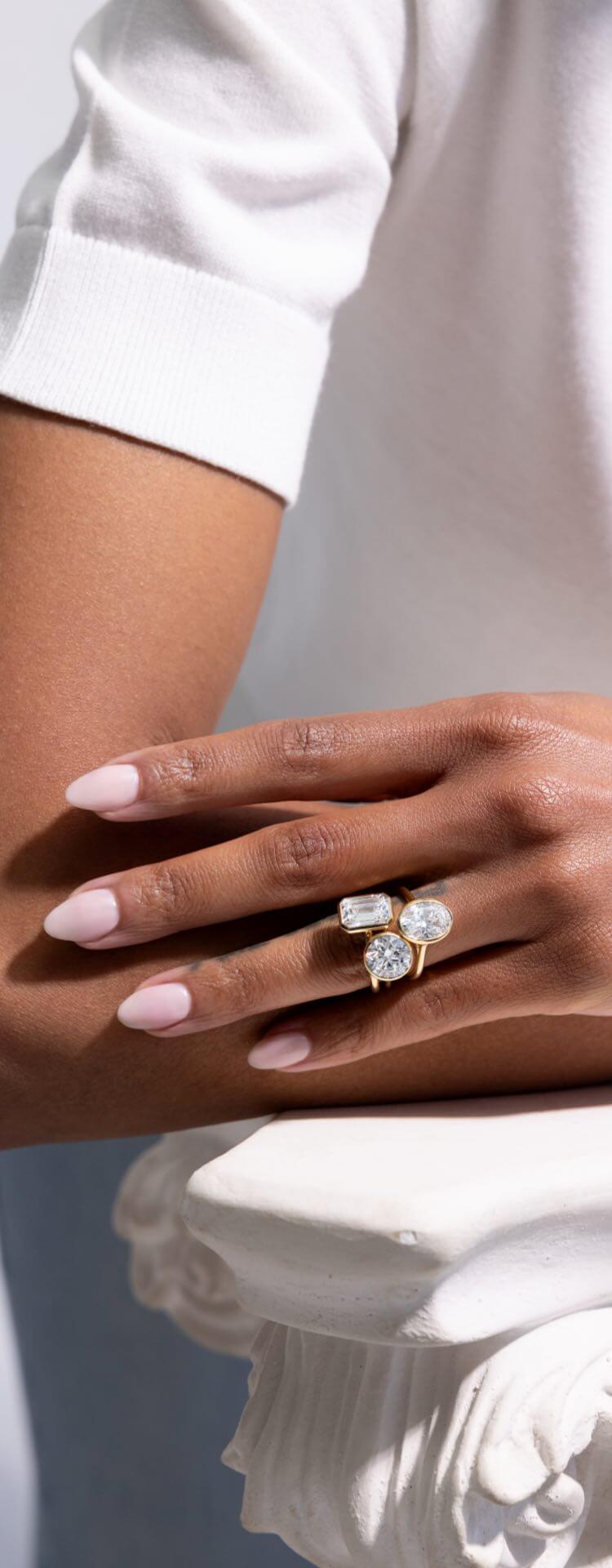 Close-up of Woman’s hand wearing bezel set lab-grown diamond engagement ring by Jean Dousset